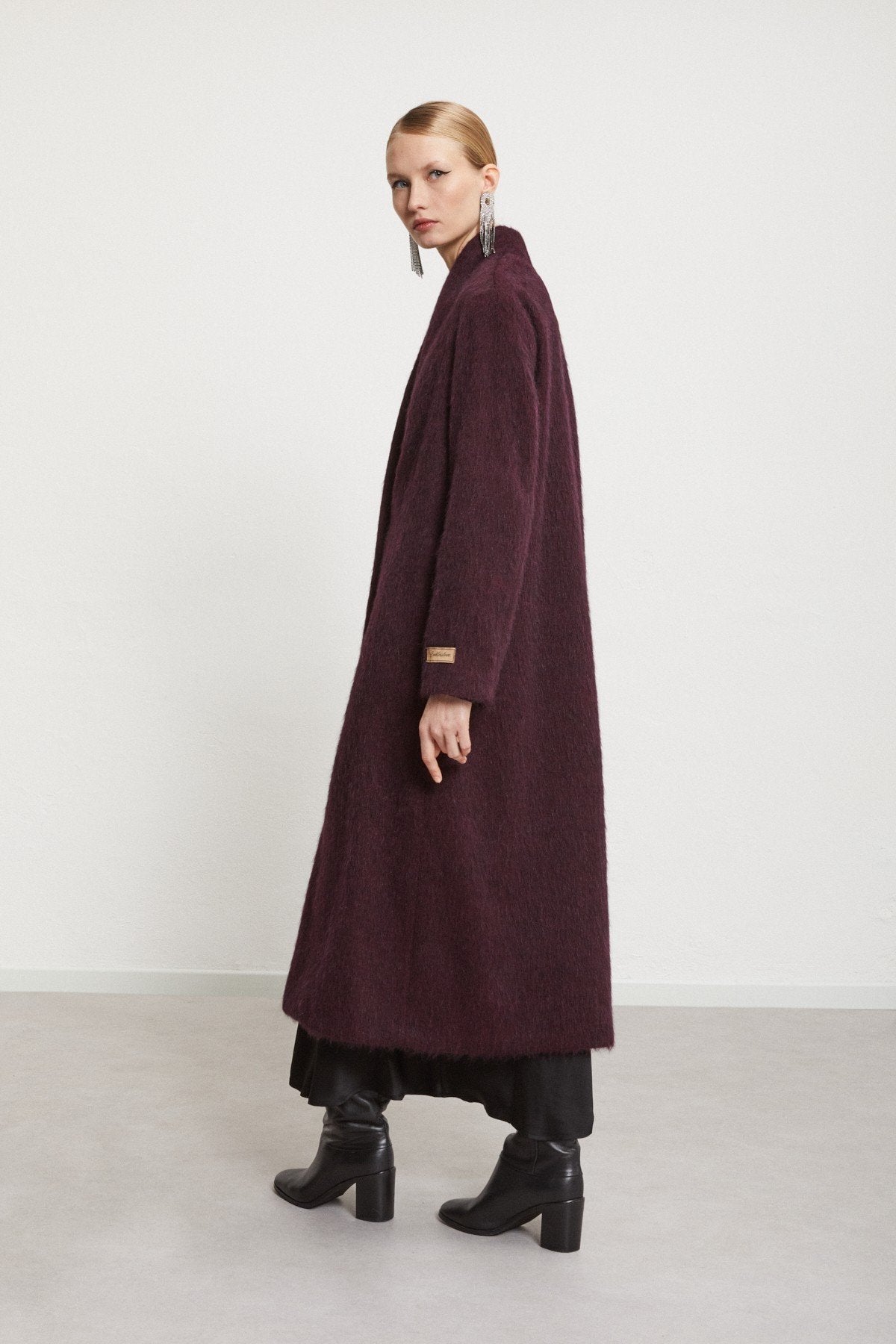 Back view of the burgundy longline coat with a minimalist silhouette.