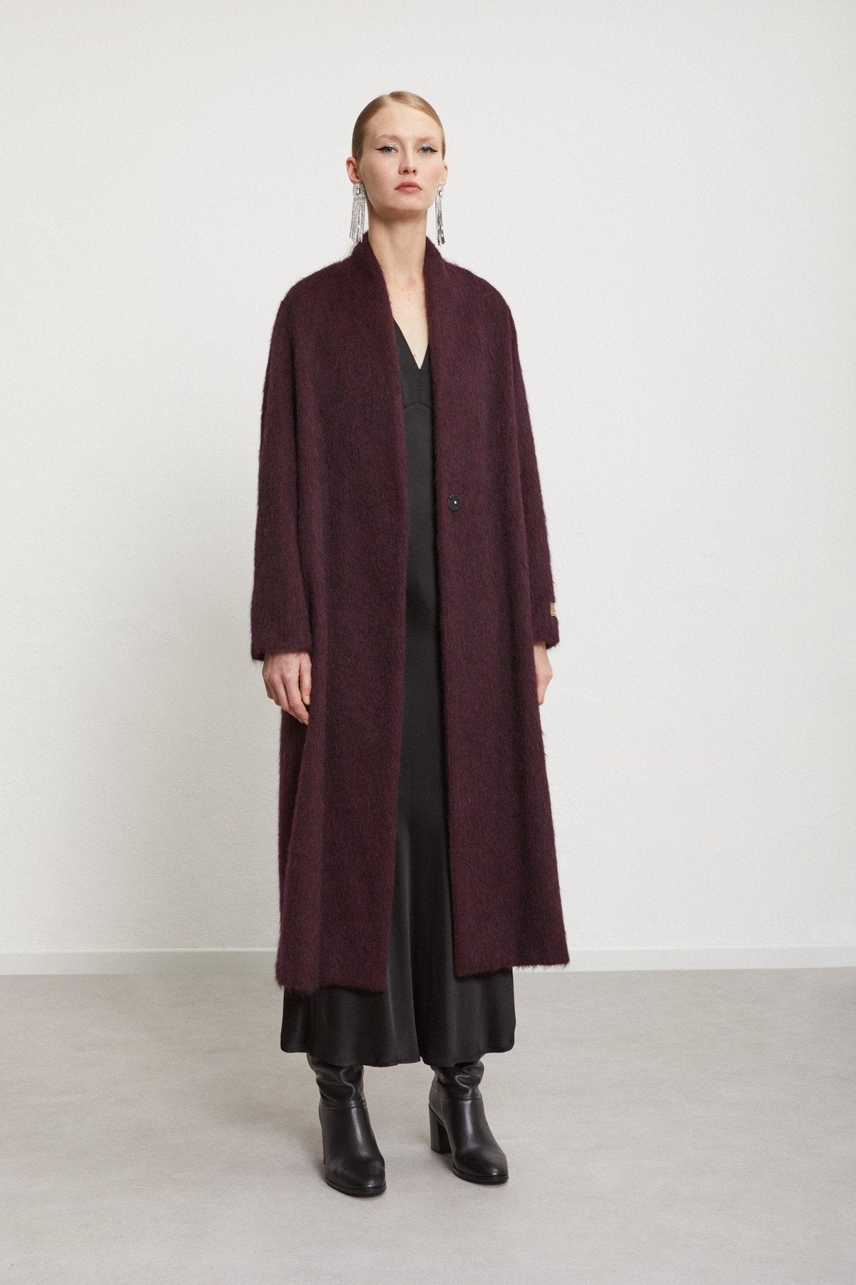 Model wearing the burgundy Ottod'Ame coat over a black evening outfit.