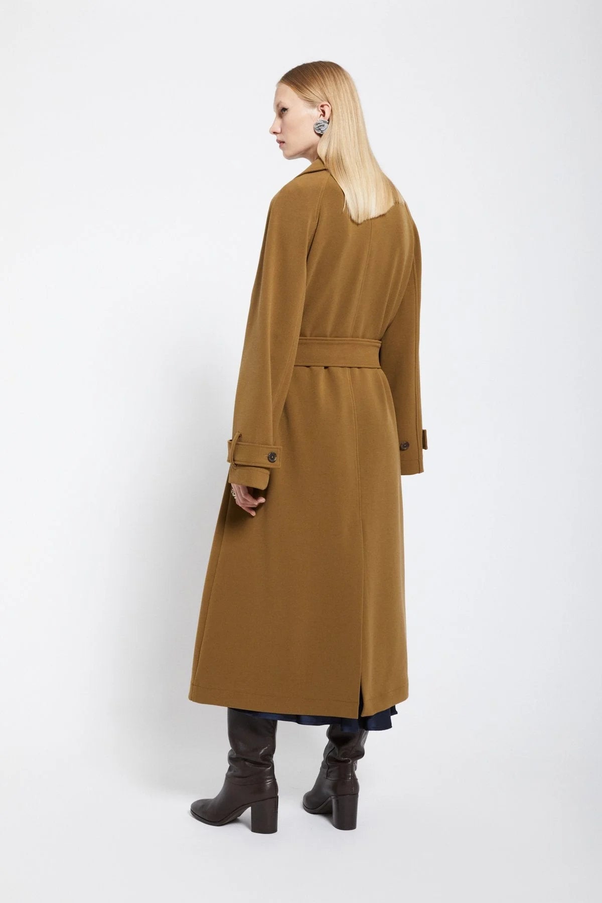 Back view of a long camel trench coat with a matching waist belt.