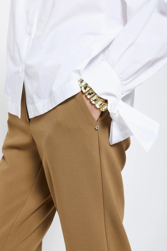 Close-up of Ottod’Ame camel tailored trousers showing the waistband, fabric and refined tailoring