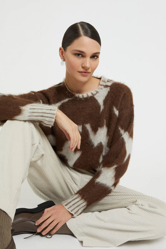 Model wearing the Ottod’Ame brown and cream cow print sweater styled with cream trousers