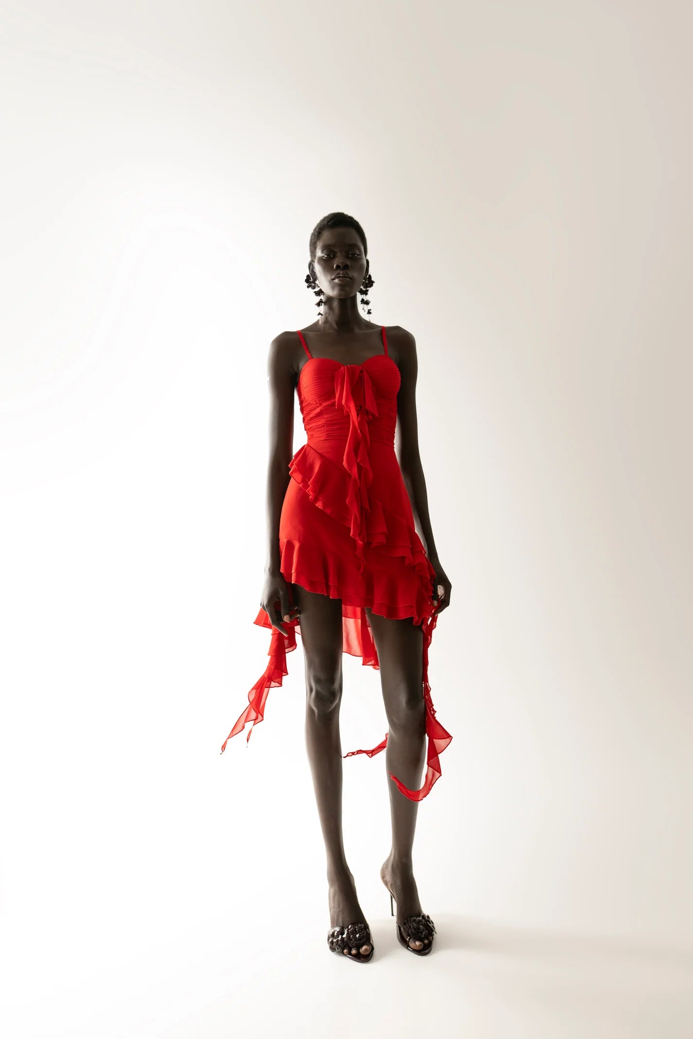 Red asymmetrical ruffle mini dress with thin straps, styled for party wear. Sophiel