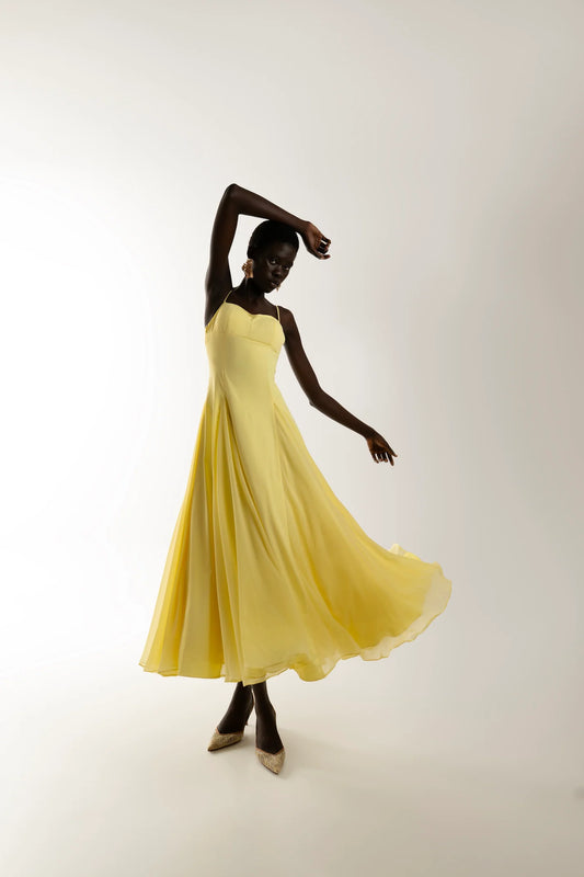 Model wearing yellow flowing maxi dress with soft movement and elegant fit. sophiel