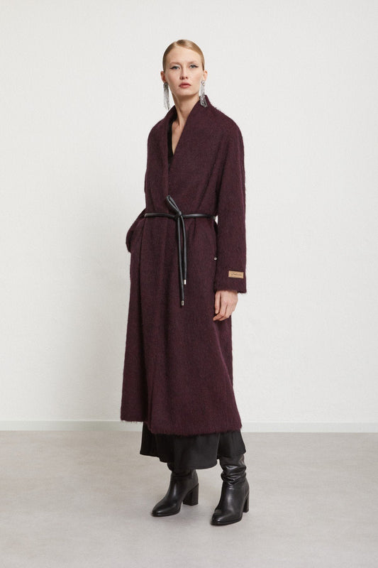 Model styling the belted burgundy coat with black ankle boots.