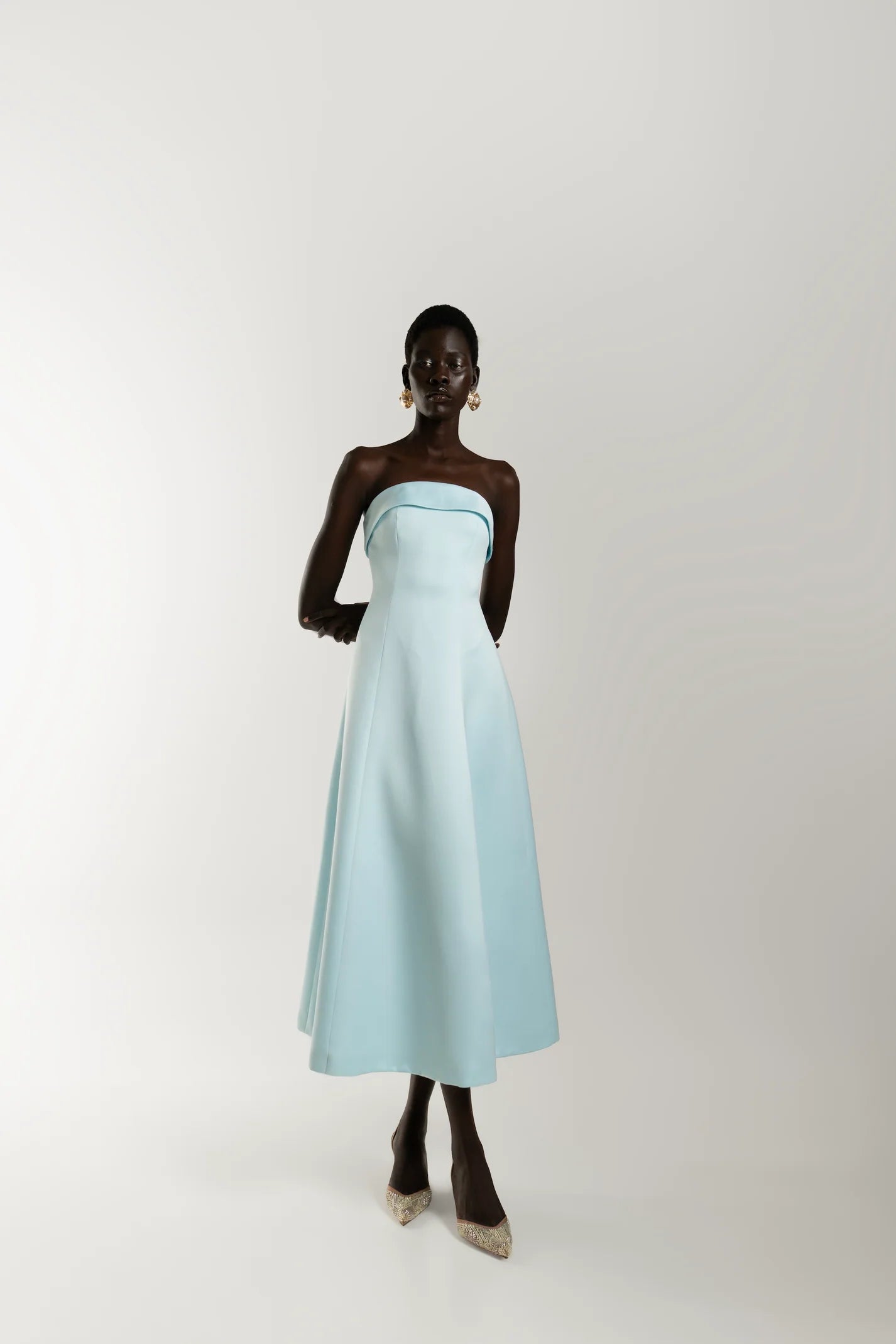 Model wearing baby blue elegant strapless midi dress with clean silhouette